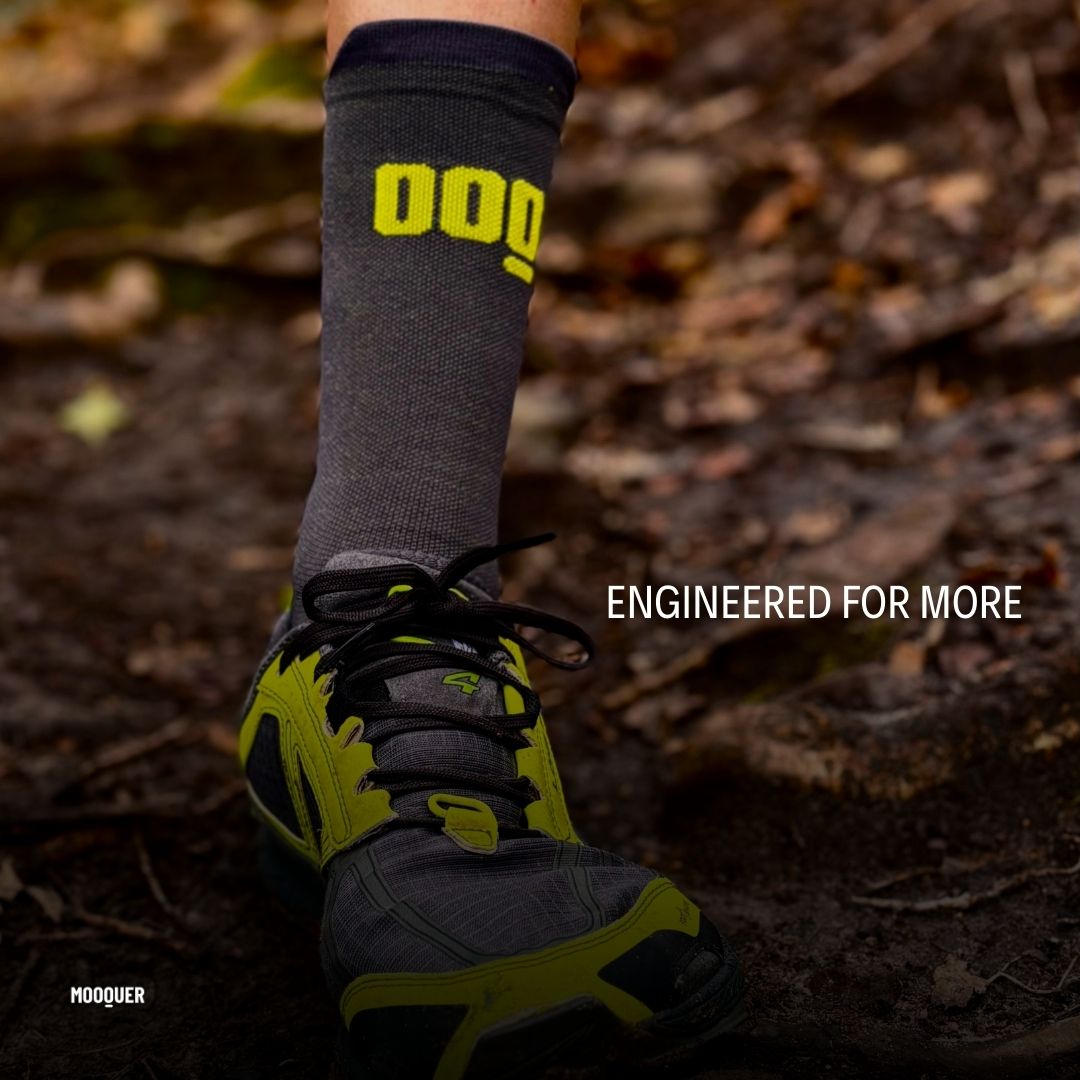 Calcetín de trail running Mooquer Trail Max con logo OOQ en sendero de bosque, primer plano de pierna y zapatilla