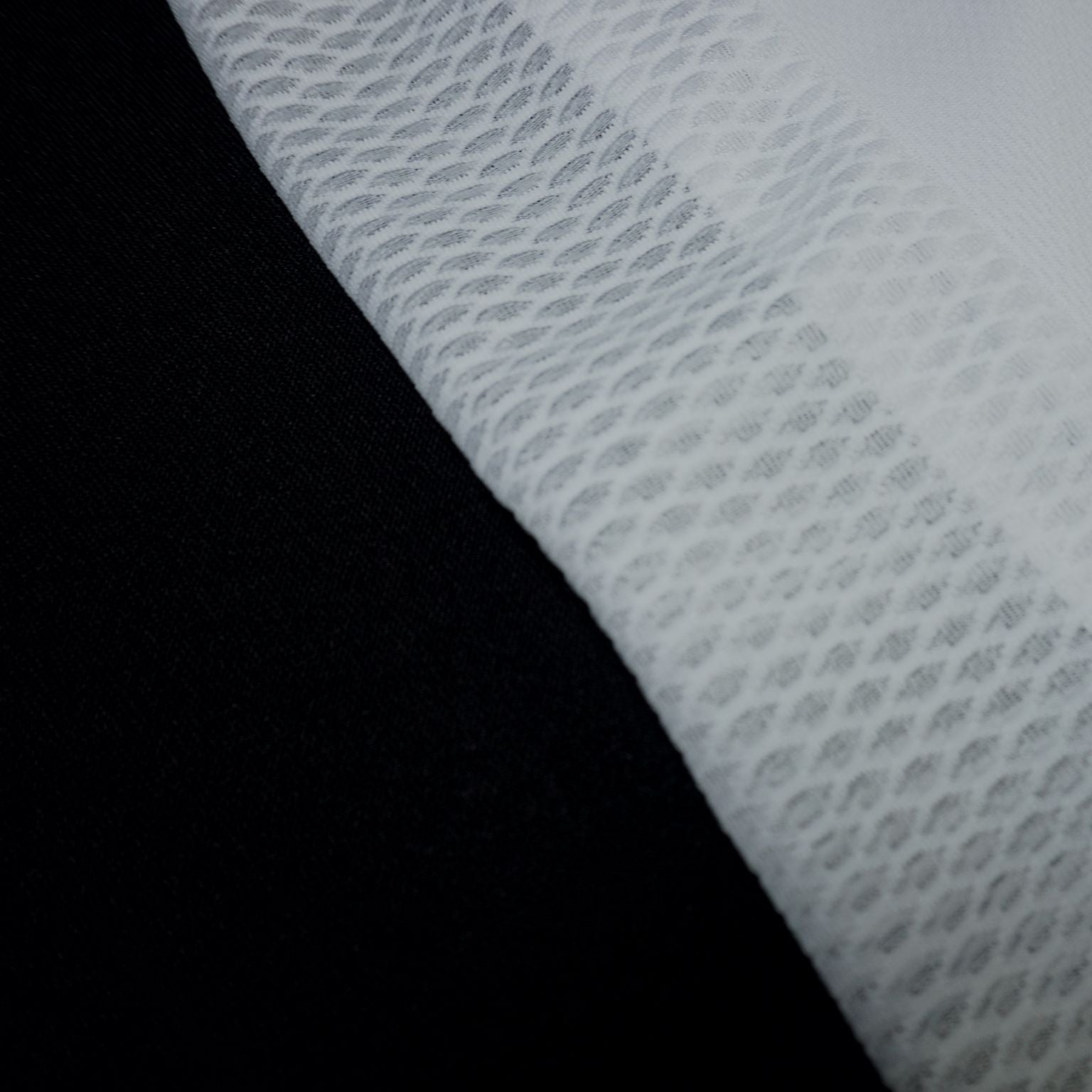 Detalle macro del bordado MOOQUER en hilo gris oscuro sobre tejido blanco de la camiseta lifestyle